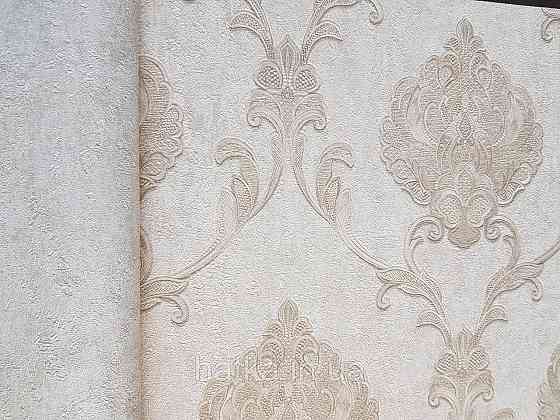Шпалери вінілові на флізеліні Grandeco Anastasia метрові вензелю завитки структурні золотисті на кремовому Київ